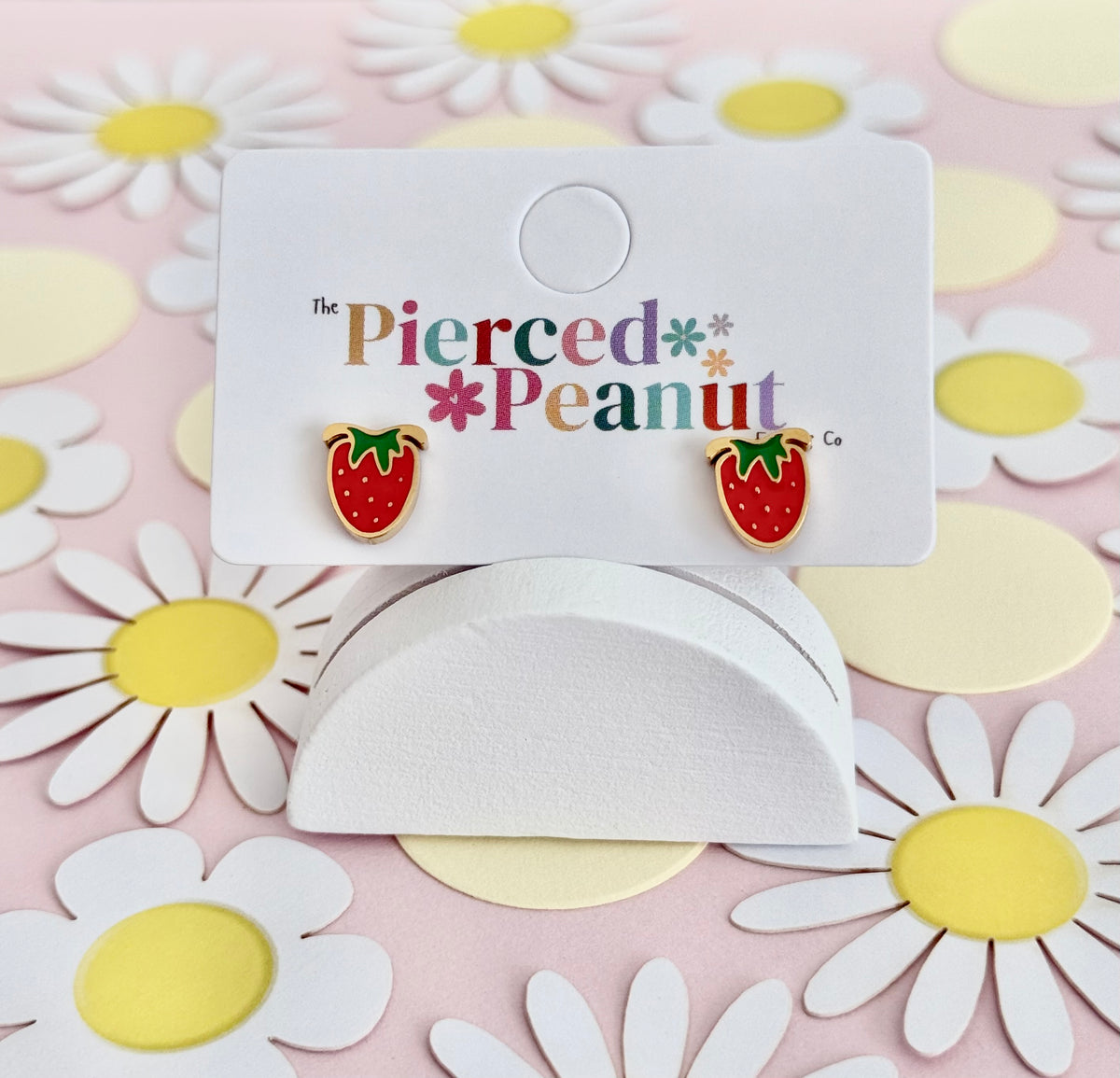 A pair of gold hypoallergenic strawberry screwback stud earrings on a display card reading the Pierced Peanut earring company.