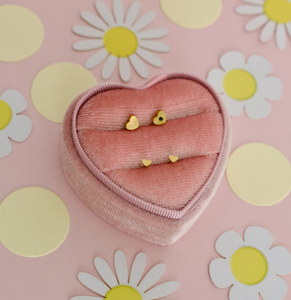 A pair of small hypoallergenic dainty heart screwback stud earrings displayed on a pink jewellery box display from the Pierced Peanut earring co.