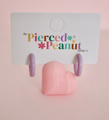 A pair of hypoallergenic hoop huggie earrings displayed on a white backing card with the brand name 'The Pierced Peanut Earring Co' printed in colorful text. 