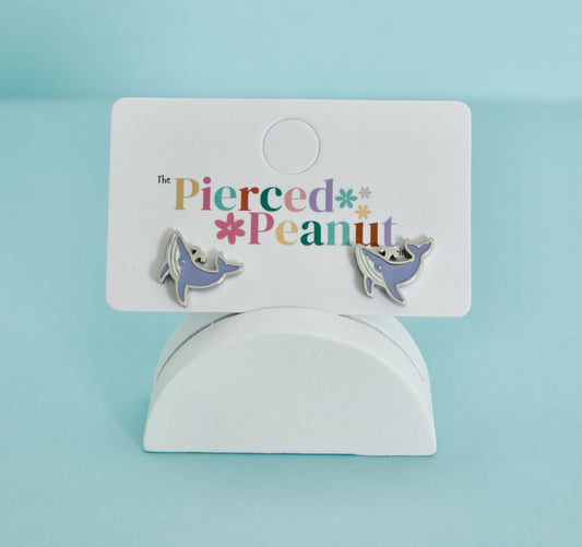 A pair of kids hypoallergenic, silver, whale-shaped screwback stud earrings with enamel blue details on a jewellery card from The Pierced Peanut Earring Co.