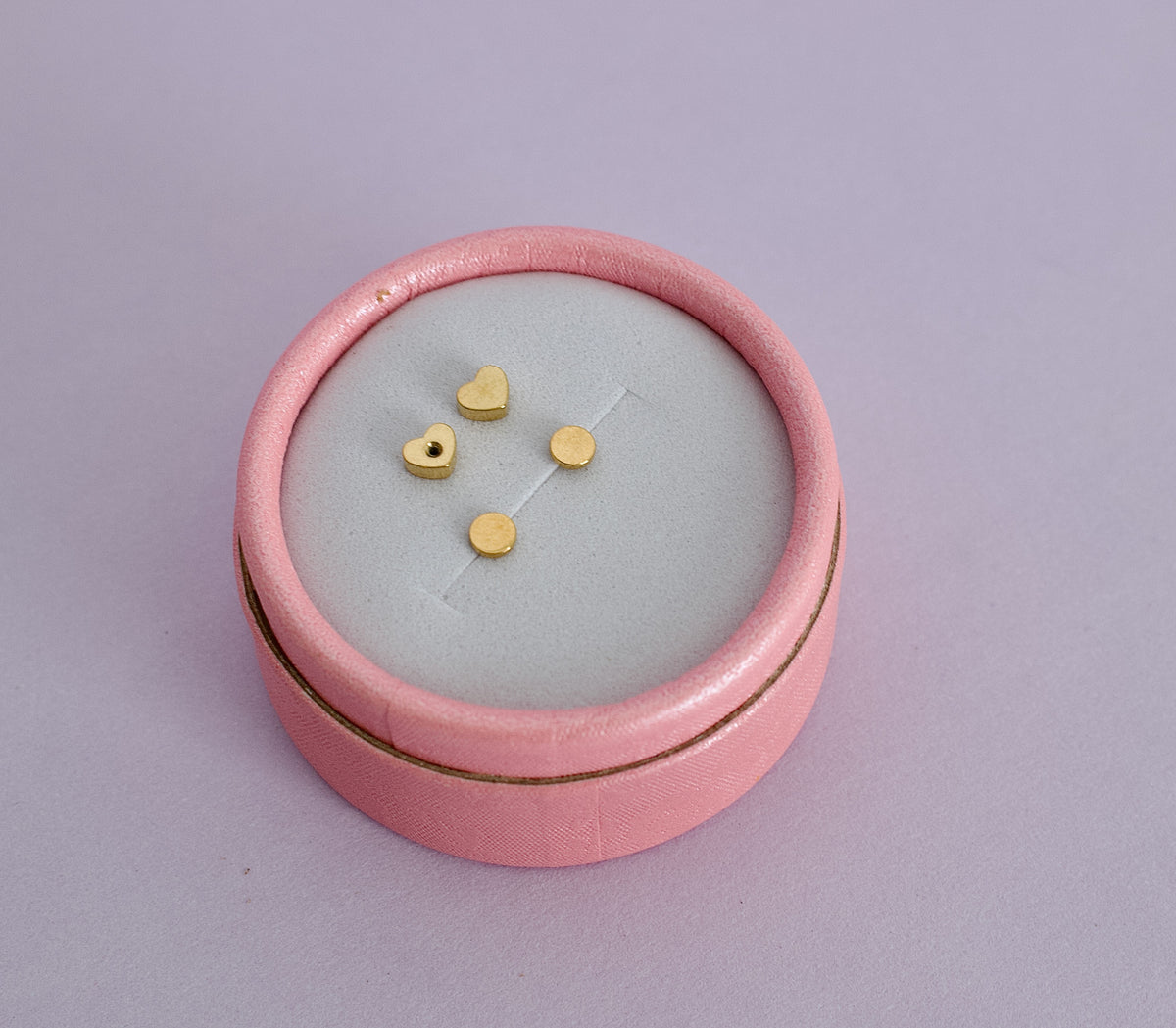 A pair of kids hypoallergenic gold flat disc screwback stud earrings. Displayed in a pink box from the Pierced Peanut earring co in Nz.