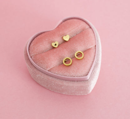 Two small gold open circle, halo ring stud earrings on a pink heart box. The earrings are for kids, made from hypoallergenic materials and are screwback studs from the Pierced Peanut Earring Co in New Zealand.