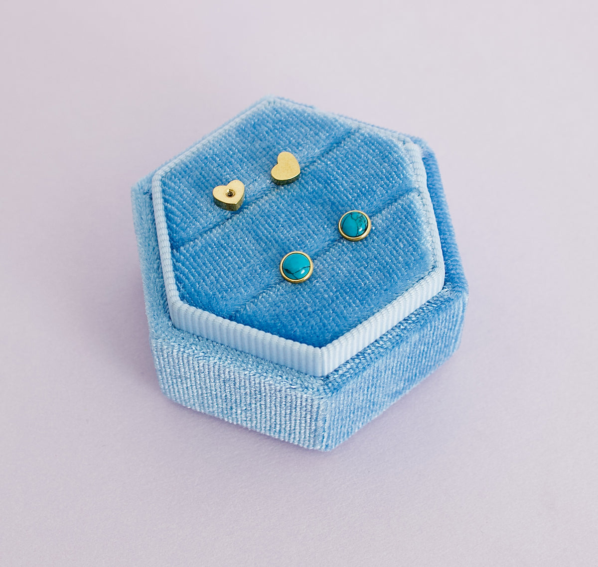 A pair of kids hypoallergenic blue marble and gold screwback stud earrings from The Pierced Peanut in Nz. Displayed on a blue ring box with the heart shaped screwbacks displayed above.