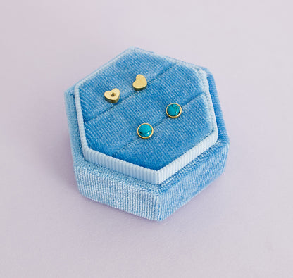 A pair of kids hypoallergenic blue marble and gold screwback stud earrings from The Pierced Peanut in Nz. Displayed on a blue ring box with the heart shaped screwbacks displayed above.