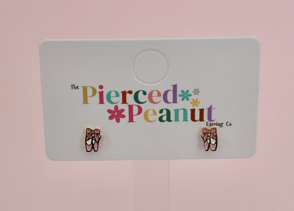 A pair of kids hypoallergenic gold ballet shoe stud earrings displayed on a white branded card reading the Pierced Peanut earring co based in NZ.
