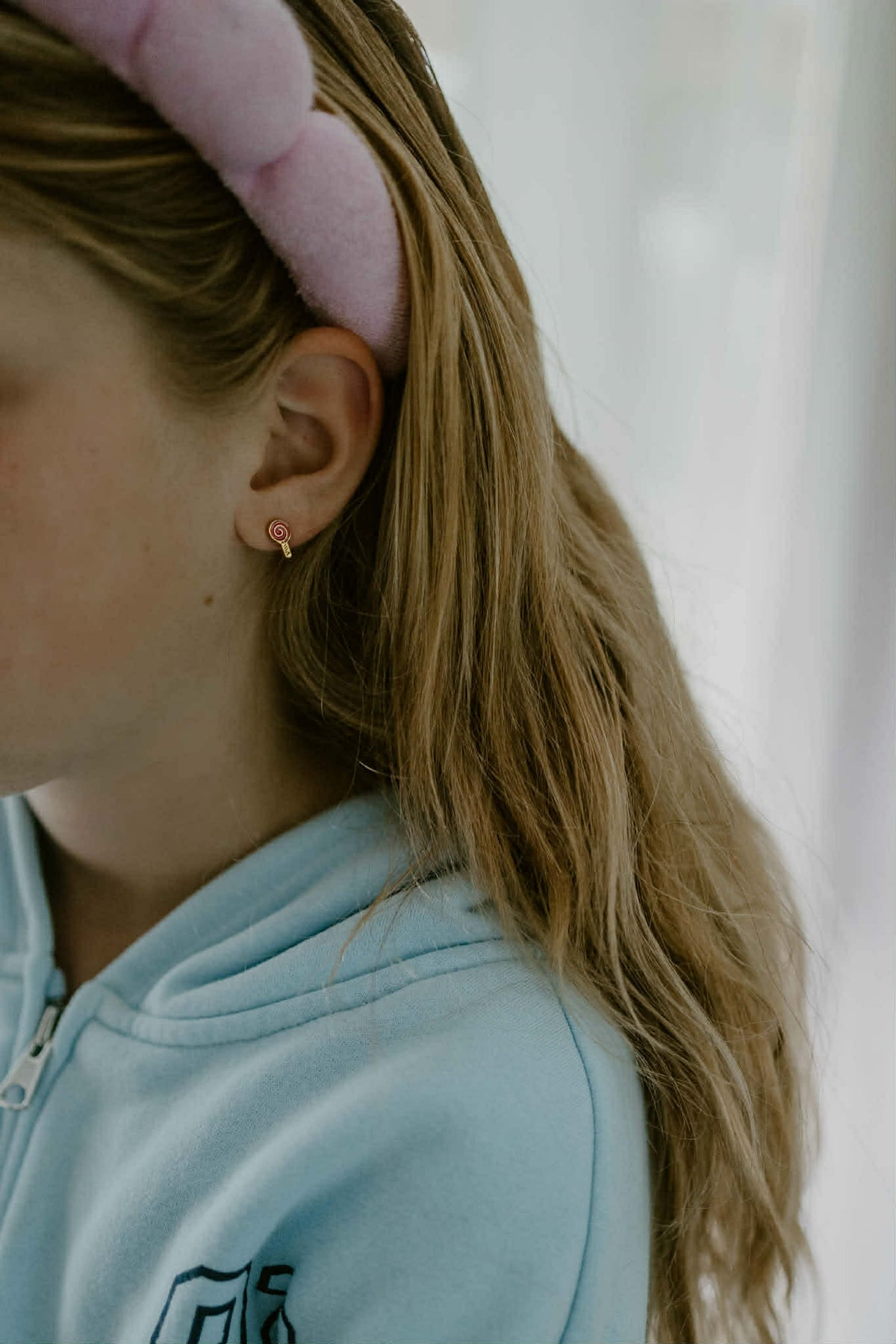 A close-up side profile of the Pierced Peanut earring co's lollipop gold screwback stud earrings being worn.